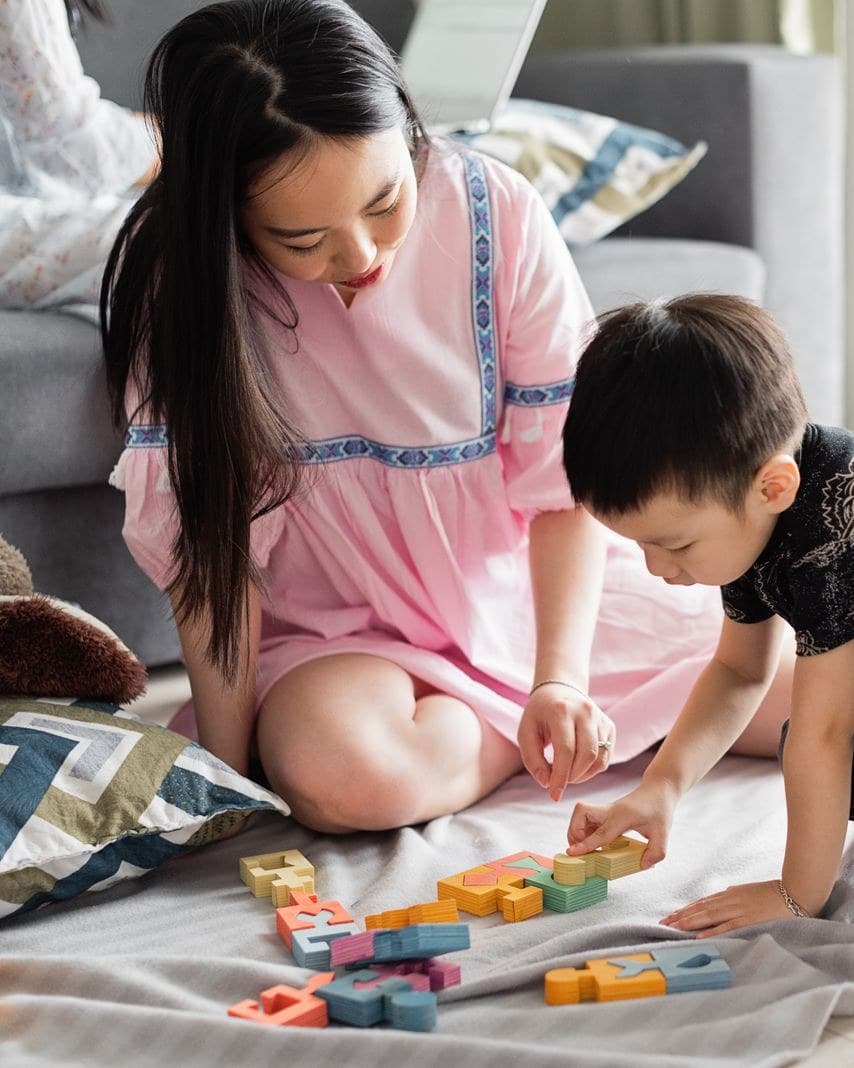 A helper sitting on the floor playing with a young child